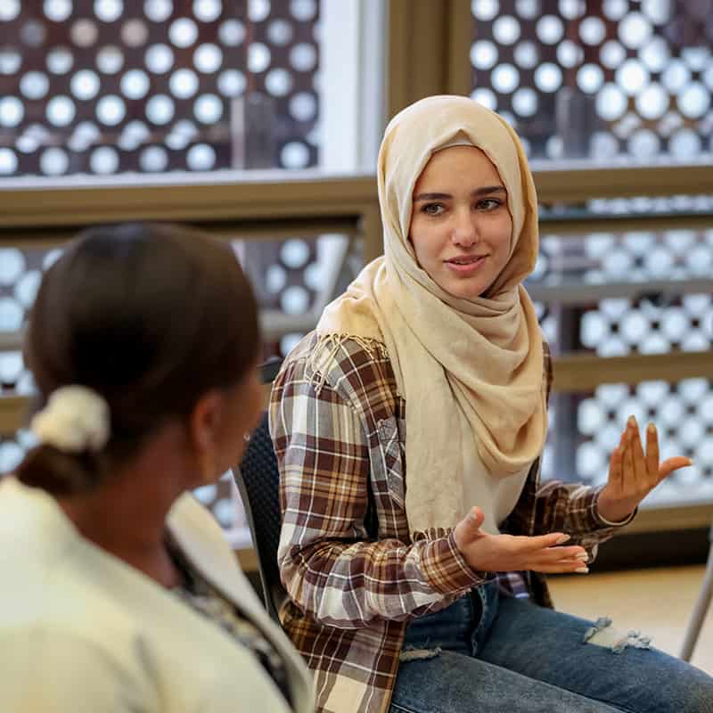 Muslim college students talking to a group in a counseling session - mental health concepts