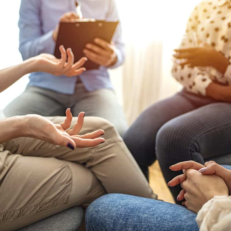 Emotional woman sharing her story during support session for addicts, close up on gesticulating hands. Close-up of therapist's hands explaining a problem to his patients